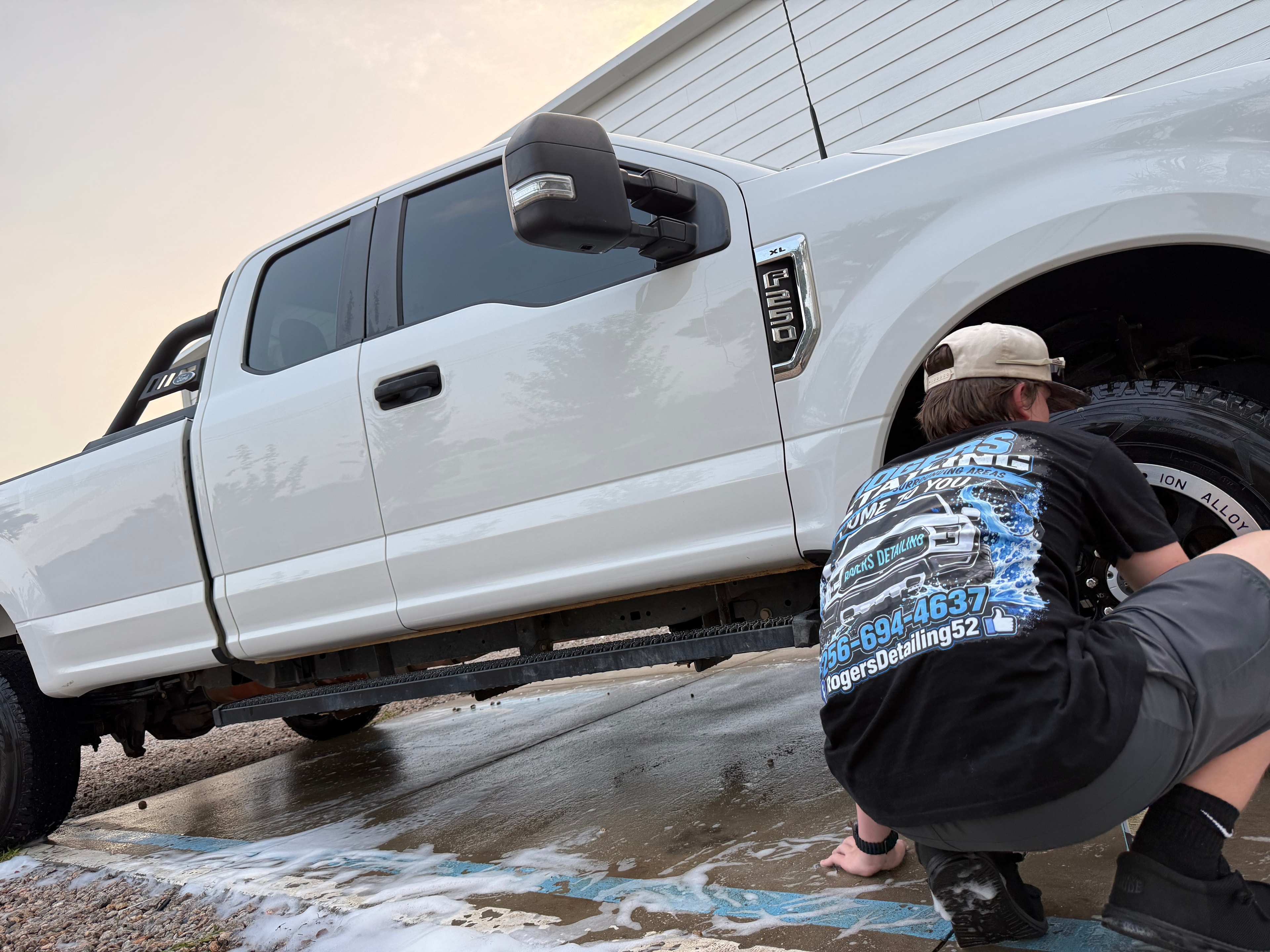 Rogers Detailing technician cleaning wheels on white Ford F-250